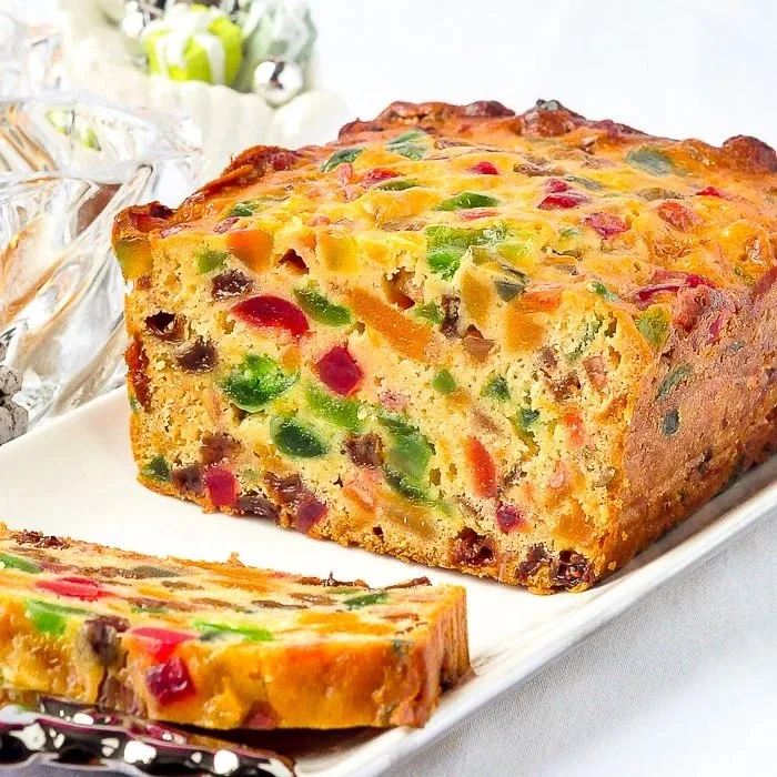 Sliced apricot fruitcake drizzled with honey glaze on a rustic wooden table.