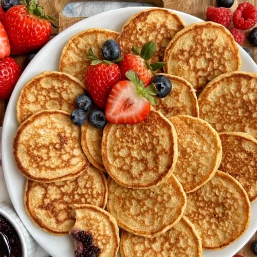 Fluffy cottage cheese pancakes made in a blender, served with syrup and berries