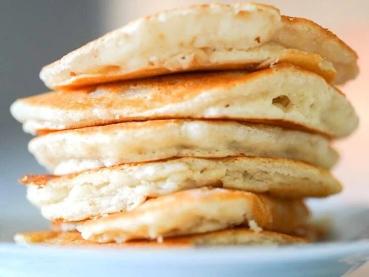 Stack of fluffy pancakes without eggs drizzled with syrup and topped with berries
