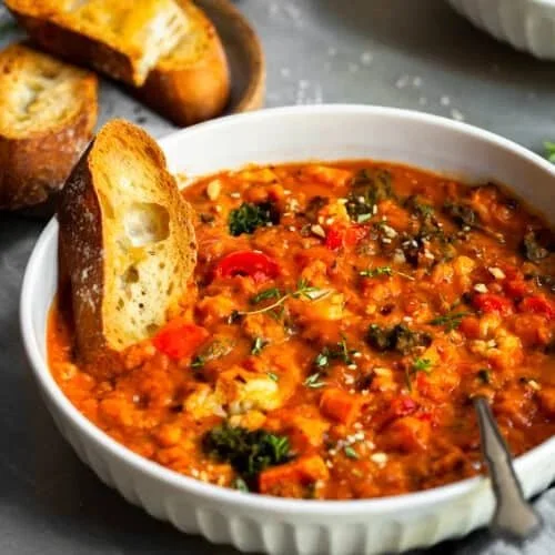 Bowl of Roasted Garlic Tomato Lentil Stew topped with fresh herbs