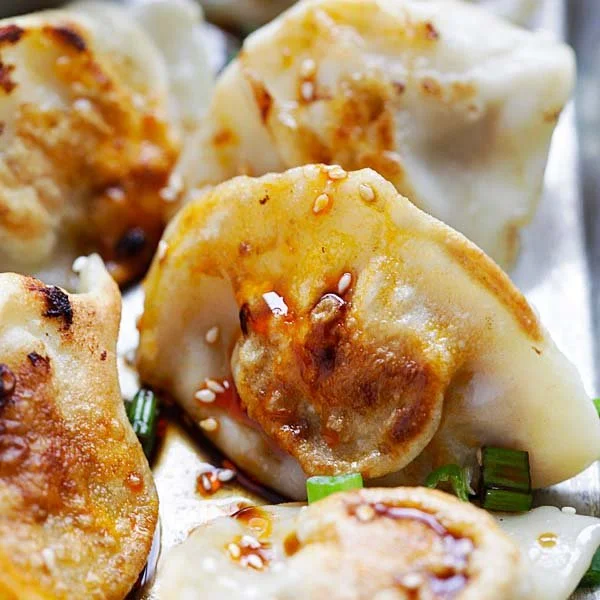 Savory chicken dumplings served in a bowl with herbs and dipping sauce