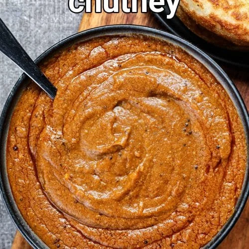 A jar of smoky roasted pepper chutney surrounded by fresh ingredients